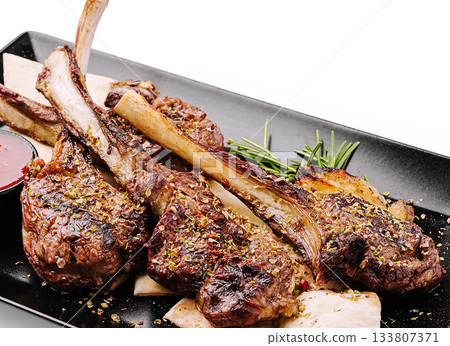 Delicious grilled lamb chops served with herbs and sauce 133807371