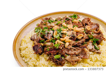 Savory dish of tender meat served on a bed of seasoned rice with herbs and nuts 133807373