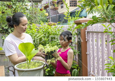 Woman and a girl are holding plants in a pot Woman and a girl are holding plants in a pot 133807443