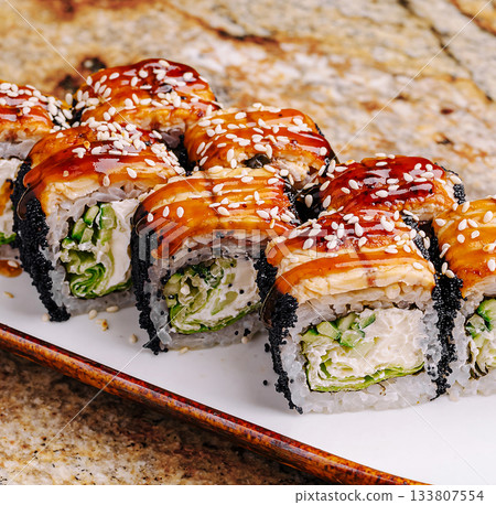 Delicious sushi rolls served on a white plate with sesame seeds on top 133807554
