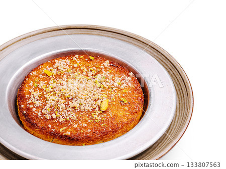 Delicious dessert featuring traditional kunafa topped with nuts and syrup 133807563