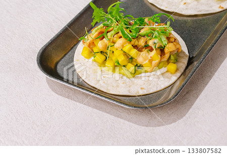 Fresh taco with chicken, mango, and herbs on a metal tray Fresh taco with chicken, mango, and herbs on a metal tray 133807582
