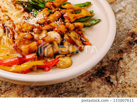 Colorful stir-fried vegetables with chicken and noodles on a plate Colorful stir-fried vegetables with chicken and noodles on a plate 133807611