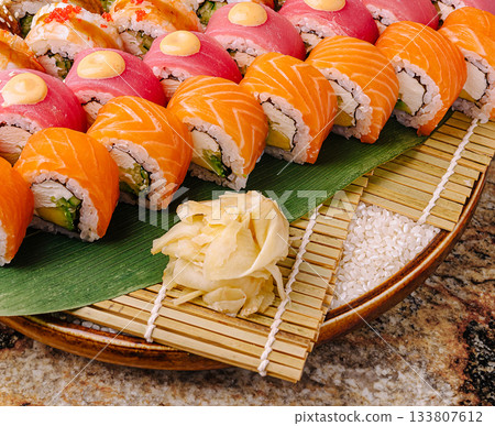 Delicious sushi assortment on a bamboo mat with pickled ginger garnish Delicious sushi assortment on a bamboo mat with pickled ginger garnish 133807612