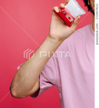 Man holding a colorful drink against a vibrant pink background Man holding a colorful drink against a vibrant pink background 133807631