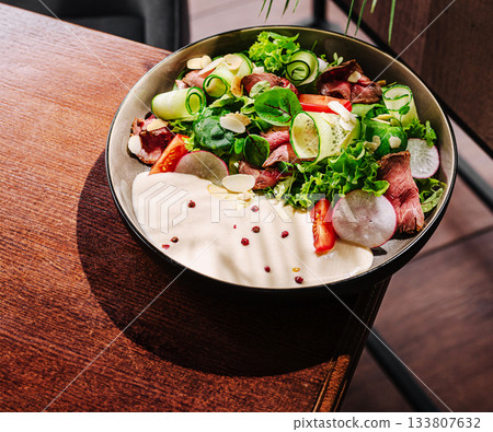 Fresh garden salad with roasted beef on a wooden table at a modern restaurant 133807632