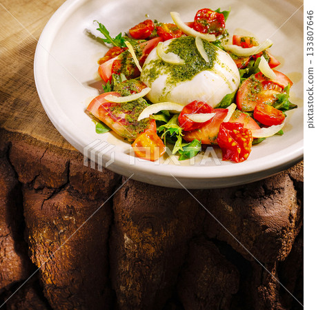 Fresh salad with burrata cheese on rustic wooden table during daylight Fresh salad with burrata cheese on rustic wooden table during daylight 133807646