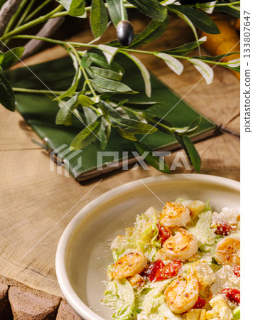 Fresh salad with grilled shrimp and vibrant greens served on a wooden table 133807647