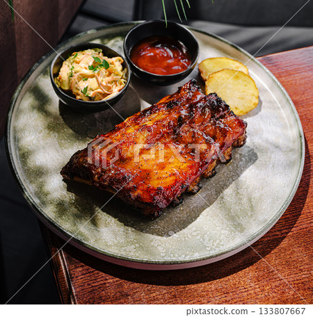 Delicious ribs with sides served in a cozy restaurant setting in the afternoon 133807667