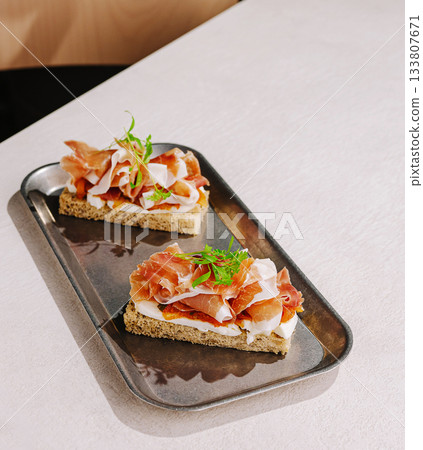 Delicious open-faced sandwiches with toppings on a modern tray 133807671