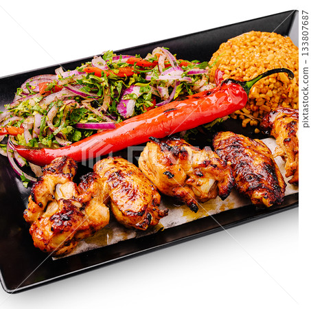 Grilled chicken with flavorful salad and spicy pepper served on black plate 133807687