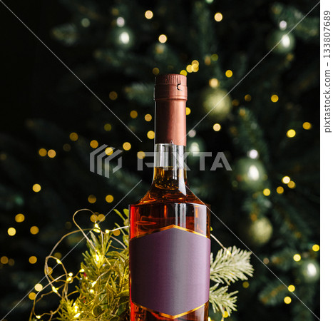 Festive bottle of wine in front of a decorated Christmas tree 133807689