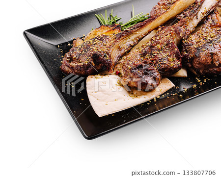 Juicy grilled lamb chops served with herbs on a black plate Juicy grilled lamb chops served with herbs on a black plate 133807706