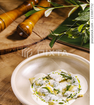 Fresh ravioli dish with creamy sauce and herbs on wooden table Fresh ravioli dish with creamy sauce and herbs on wooden table 133807732