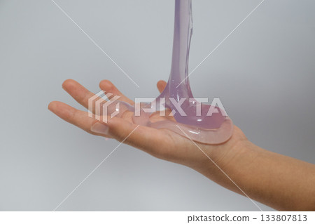 Purple slime pouring from a container into the palm of your hand Purple slime pouring from a container into the palm of your hand 133807813