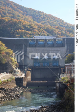 A view of blue skies, autumn leaves, mountains, a dam and a river 133808083