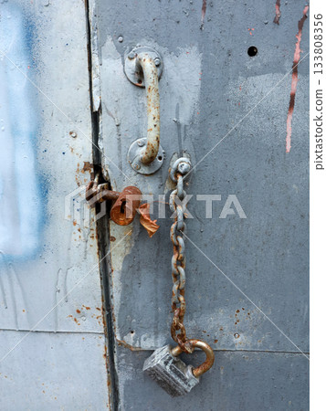 A steel chain hangs from above. Gate opening chain. Gate in the garage. A steel chain hangs from above. Gate opening chain. Gate in the garage. 133808356