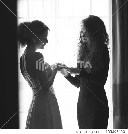 Caucasian young woman holding girlfriend's hands while standing against window at home, copy space Caucasian young woman holding girlfriend's hands while standing against window at home, copy space 133808430
