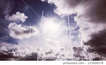 Rugby goalposts are standing under partly cloudy sky, with bright sunlight breaking through 133808576