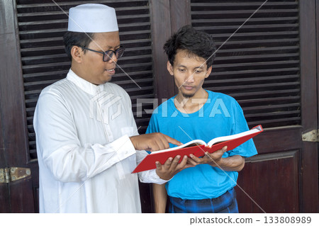 Two muslim man reading a Quran in red color together. A concept of religion for Islam 133808989