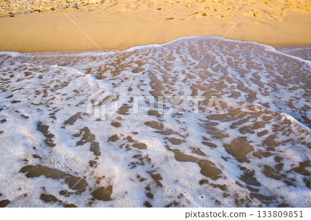 Waves lapping at the golden sand on a quiet beach in a coastal location, creating a serene environment for relaxation and reflection. Waves lapping at the golden sand on a quiet beach in a coastal location, creating a serene environment for relaxation and reflection. 133809851