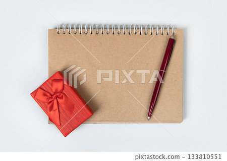 Christmas composition of red gift box and open blank notebook and pen on gray background for writing goals and plans for the New Year. Flat lay, copy space Christmas composition of red gift box and open blank notebook and pen on gray background for writing goals and plans for the New Year. Flat lay, copy space 133810551