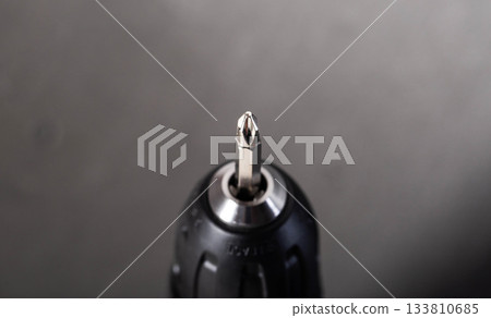 Close up view of shining metal Phillips head screwdriver bit in drill chuck, essential tool for fastening tasks 133810685