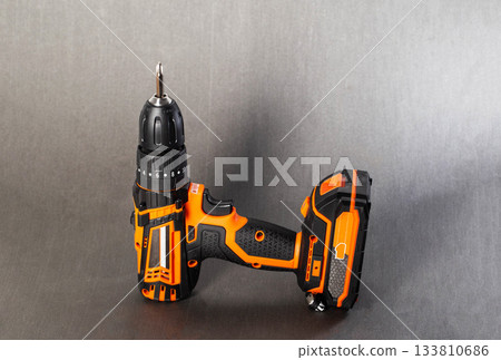 Cordless power drill with a screwdriver bit on a solid grey surface Cordless power drill with a screwdriver bit on a solid grey surface 133810686