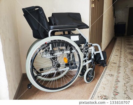 Manual wheelchair indoors, modern design, black seat and backrest, silver frame, white tires, ready for use, medical equipment for mobility, aid for disability, comfortable seating 133810707