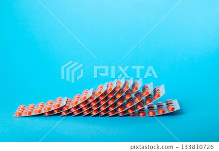 Stack of blisters with red pills on blue background. Concept of medicines for gout and arthritis. Copy space for text, glucosamine 133810726