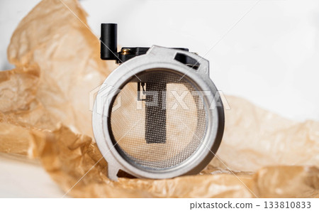 Modern electronic mass air flow sensor on brown paper, close-up. Car spare part, industry 133810833