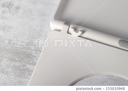 Broken hinge on white toilet seat and lid, close-up, industry, low quality plastic 133810948
