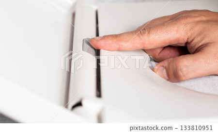 Close-up of finger pressing button on modern toilet seat cover to remove and disengage, close-up Close-up of finger pressing button on modern toilet seat cover to remove and disengage, close-up 133810951