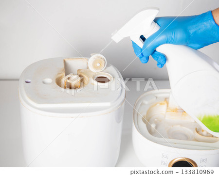 Spraying a chemical rust and scale remover into a humidifier. Home humidifier maintenance, close-up 133810969