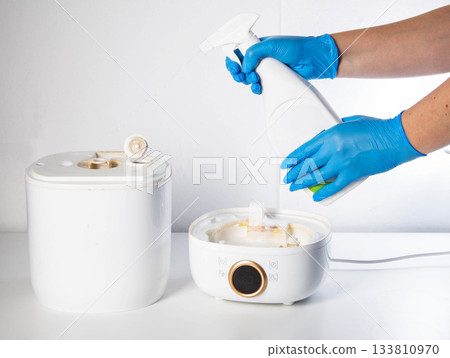 Spraying a chemical rust and scale remover into a humidifier. Home humidifier maintenance, close-up. Copy space for text 133810970
