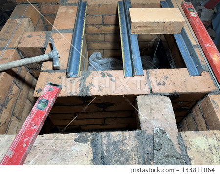 Brickwork of a heating stove. Channels for dividing and passing smoke. Stove fitters tools. Close-up. Brickwork of a heating stove. Channels for dividing and passing smoke. Stove fitters tools. Close-up. 133811064