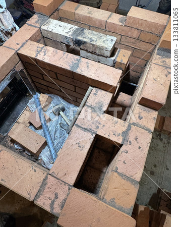 Brickwork of a heating stove. Channels for dividing and passing smoke. Cooking plate. Close-up. Brickwork of a heating stove. Channels for dividing and passing smoke. Cooking plate. Close-up. 133811065