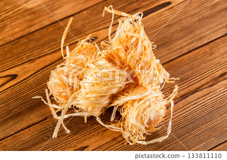 Wooden rolls for starting a fire, stove, or barbecue, soaked in paraffin, on a wooden background, close-up 133811110