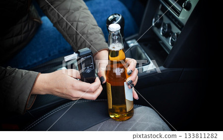 Driver In Vehicle Holds Beer And Breathalyzer. Illustrating The Risk Of Impaired Driving. Driving license revocation for alcohol 133811282