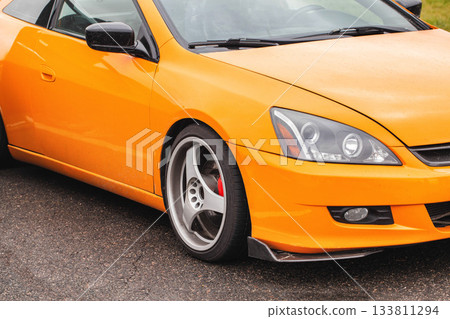 Modern Orange Coupe With Custom Modifications Parked On Wet Road. Closeup View Of Its Side Profile. 133811294