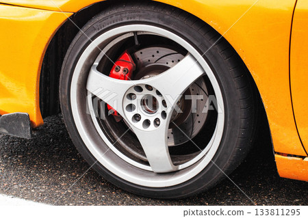 Detailed Look At Custom Silver Alloy Wheel With Red Brake Caliper. Performance Car Shows Off Its Sporty Rim. 133811295