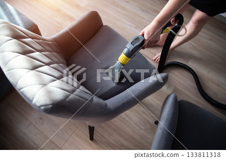 Professional upholstery cleaning in a modern living room with gray chairs and wooden floor in daylight Professional upholstery cleaning in a modern living room with gray chairs and wooden floor in daylight 133811318