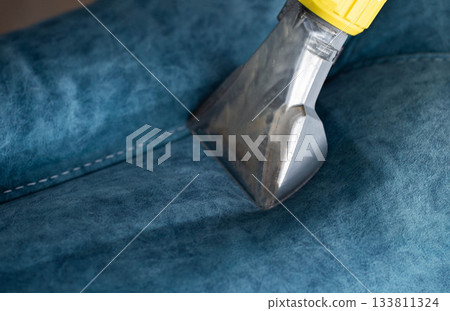 Cleaning a blue upholstery surface with a professional tool in a bright, well-lit room during the day 133811324