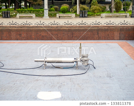 Empty fountain in a city park. Draining the fountain. Cleaning the fountain with a hose. Empty fountain in a city park. Draining the fountain. Cleaning the fountain with a hose. 133811378