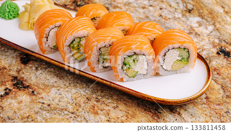 Sushi rolls with fresh salmon on a white plate displayed on a granite table 133811458