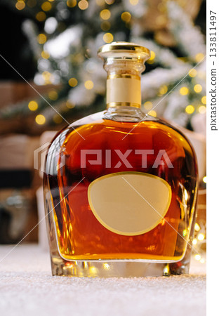 Elegant glass decanter filled with amber liquid beside holiday decorations 133811497