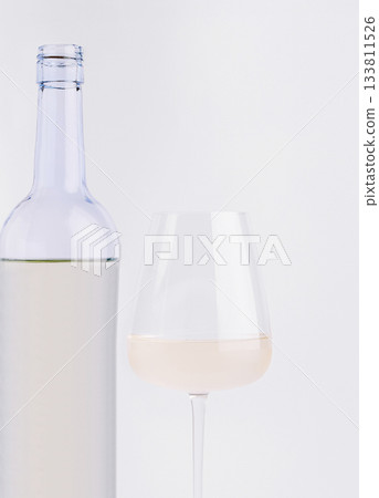 Glass of white wine beside a clear bottle on a neutral background Glass of white wine beside a clear bottle on a neutral background 133811526