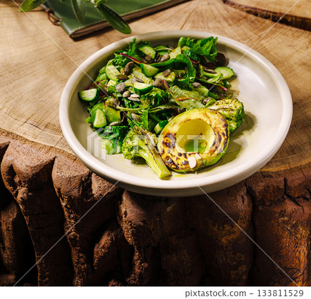 Fresh salad with grilled vegetables on a wooden table in a cozy setting Fresh salad with grilled vegetables on a wooden table in a cozy setting 133811529