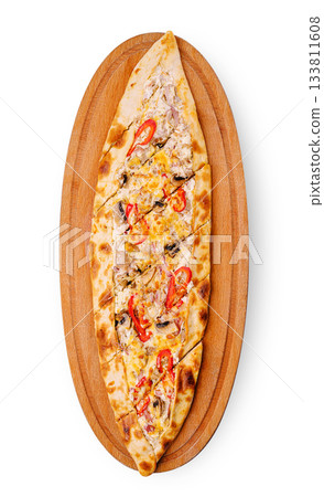 Delicious pide served on a wooden platter with colorful toppings 133811608