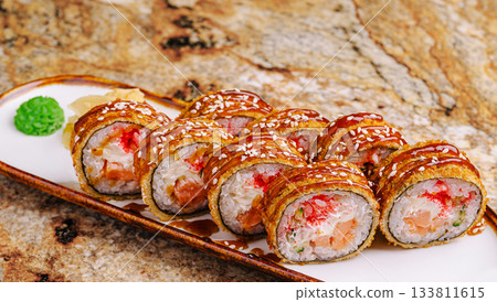 Sushi rolls topped with sauce served on a white plate Sushi rolls topped with sauce served on a white plate 133811615